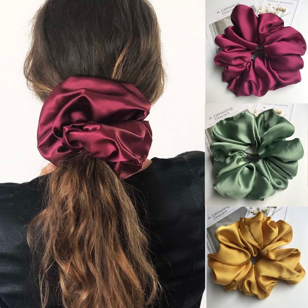Oversized smooth satin scrunchie in burgundy, green, and yellow on model's hair and display.