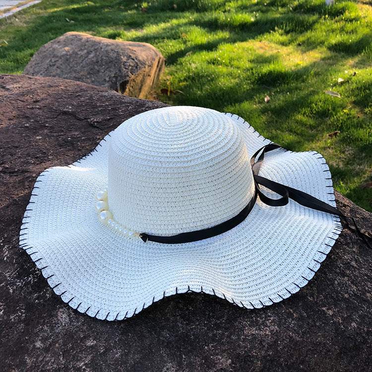 Women's straw hat with large brim and black bow, ideal for summer and suitable for various occasions.