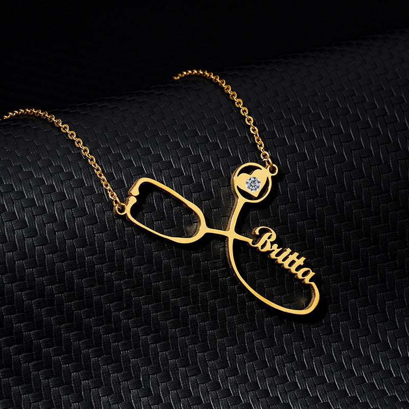 Customized gold stethoscope necklace with name pendant on dark background.