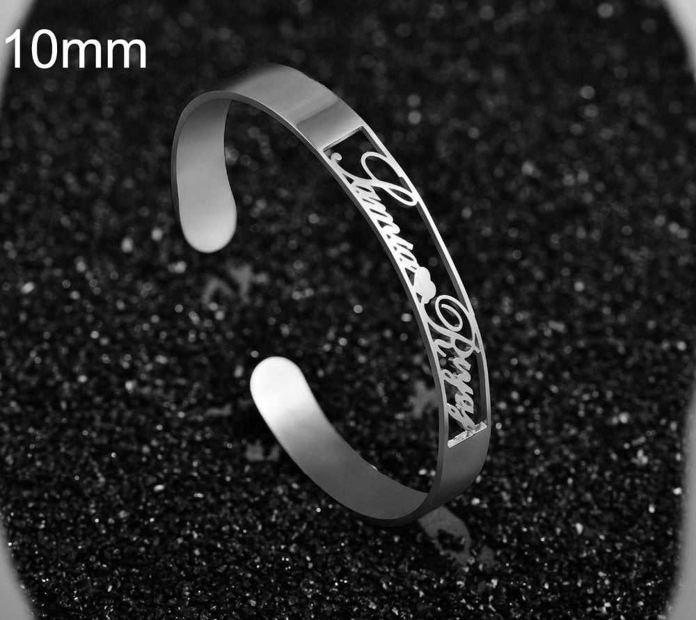 Customized stainless steel name bracelet on black background.