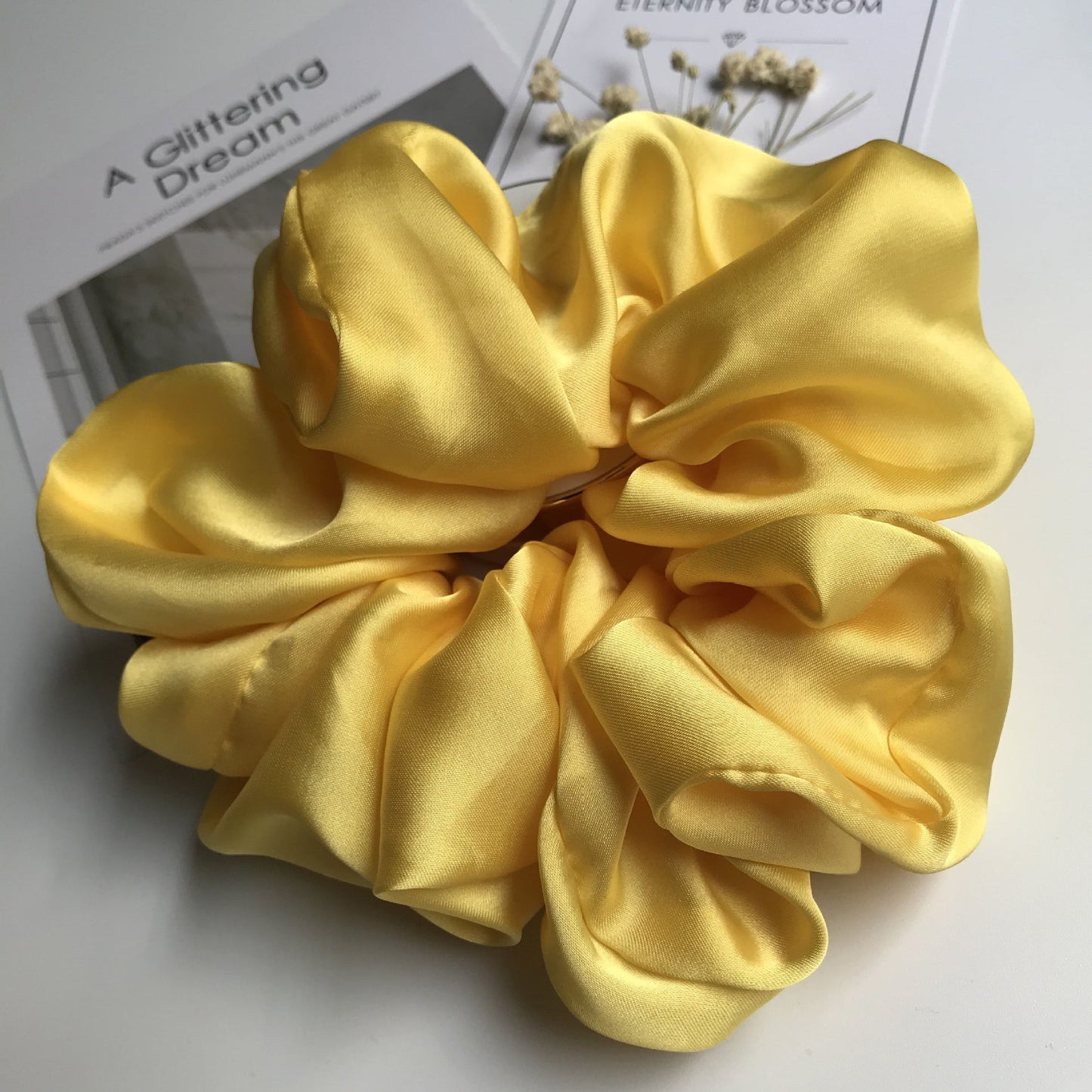 Oversized smooth satin large intestine circle hair tie in bright yellow color.