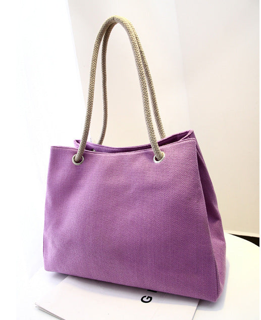 Large capacity purple shoulder bag with woven handles, cotton texture, and medium size suitable for women's fashion.