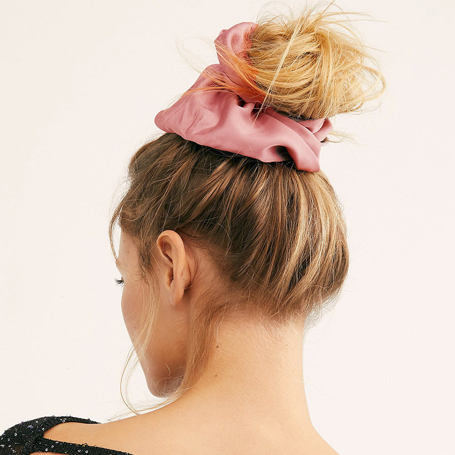Oversized smooth satin large intestine hair tie styled on a woman's bun.