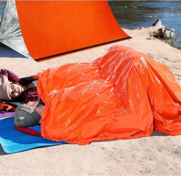 Outdoor scene with orange first aid sleeping bag, providing thermal protection.