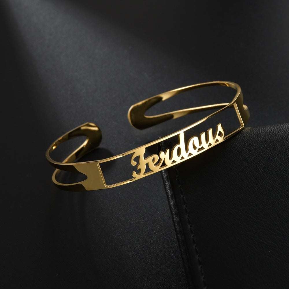 Gold stainless steel customized name bracelet on dark background.