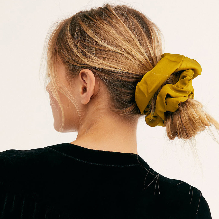 Oversized smooth satin large intestine circle hair tie in turmeric.