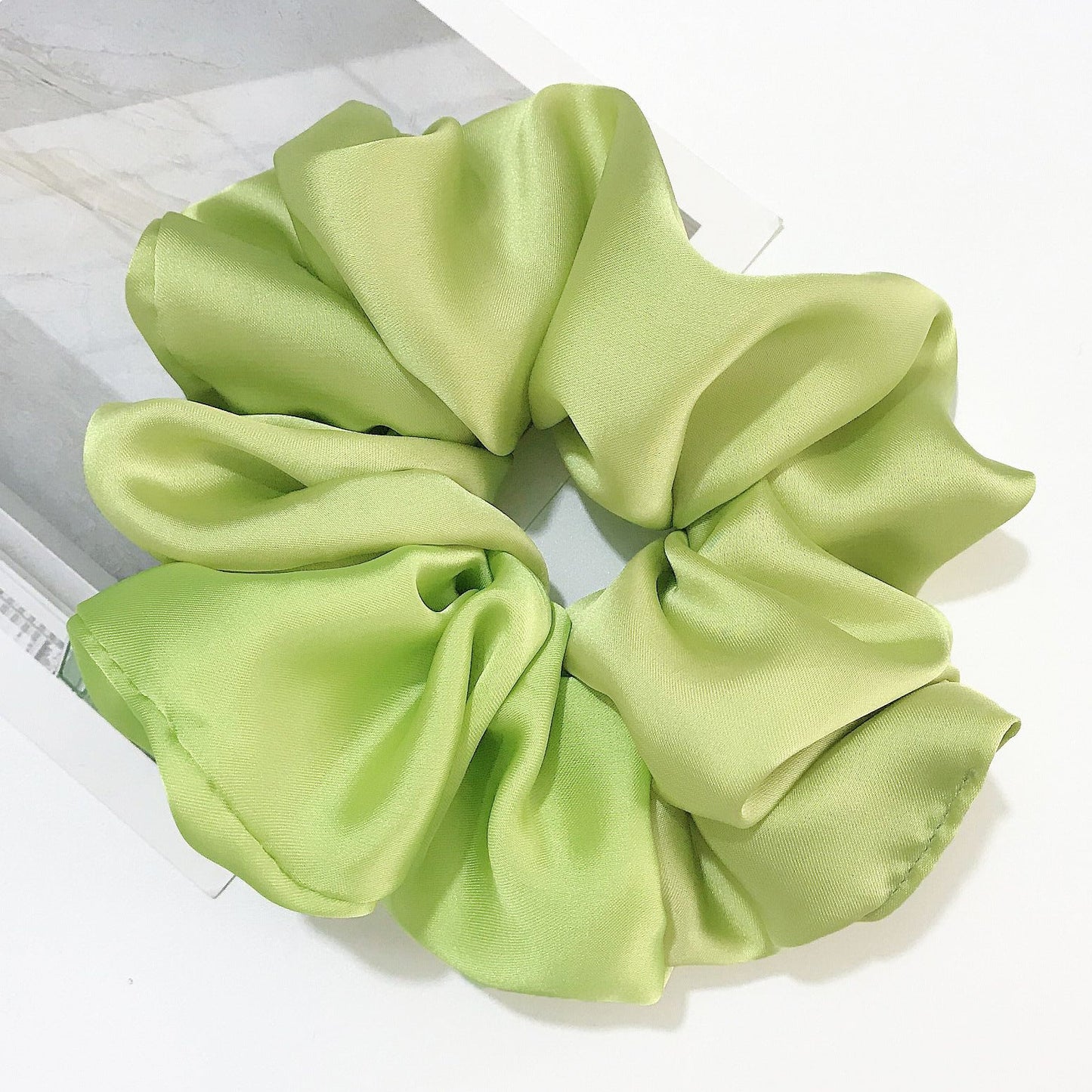 Oversized smooth satin hair tie in light green.