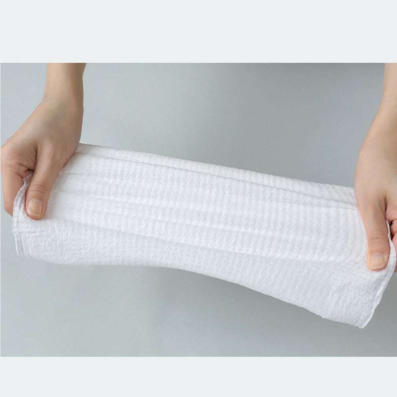 Hands holding a white compressed towel, perfect for portable and disposable facial use.
