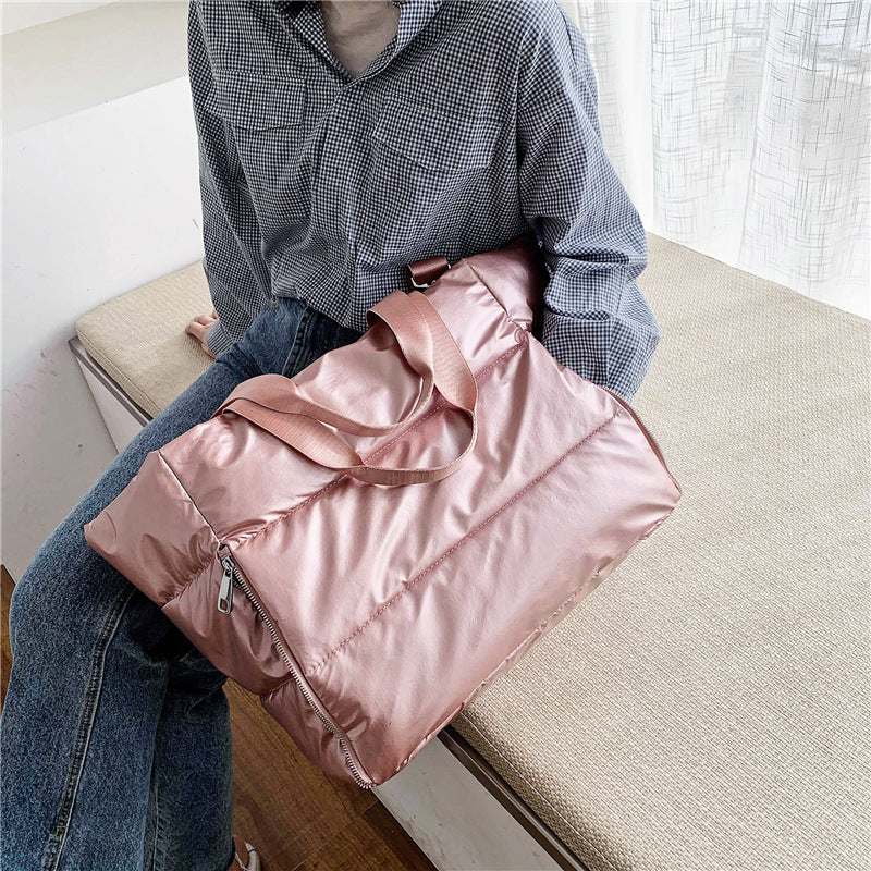 Women's gym bag in durable nylon, shown carried by a person, featuring a soft handle and stylish design.