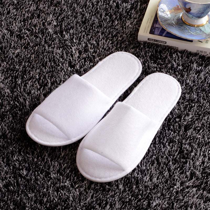White disposable hotel slippers on a gray carpet, suitable for spring and autumn.