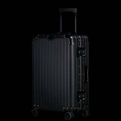 Large aluminum magnesium alloy luggage with sleek silver finish and universal wheels on black background.
