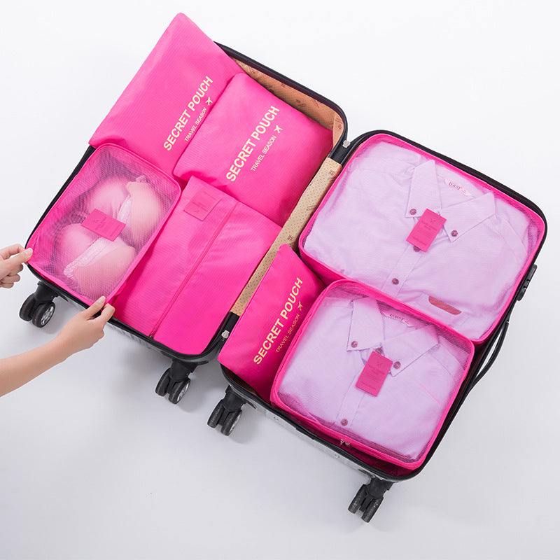 Travel luggage storage bag with pink organizing pouches, suitable for clothes and toiletries.
