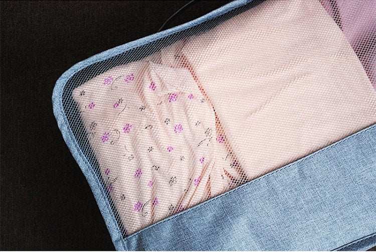 Close-up of a blue waterproof travel tote bag with mesh fabric containing folded clothes.
