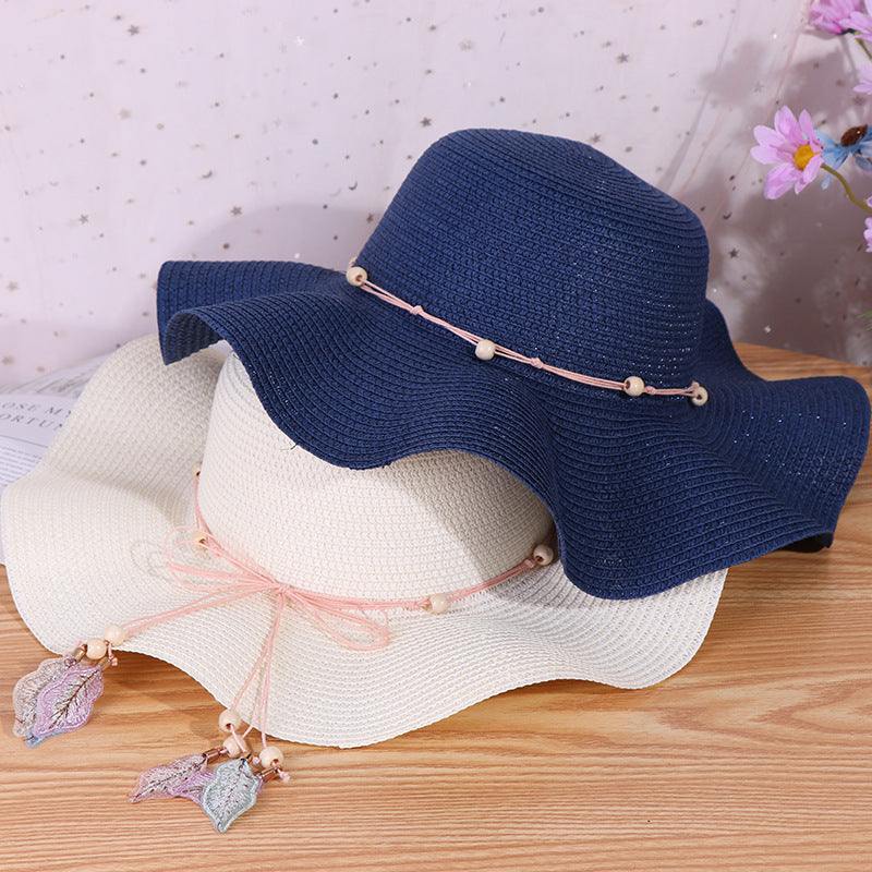 Ladies big brim wave straw hats in navy and beige with decorative bows.