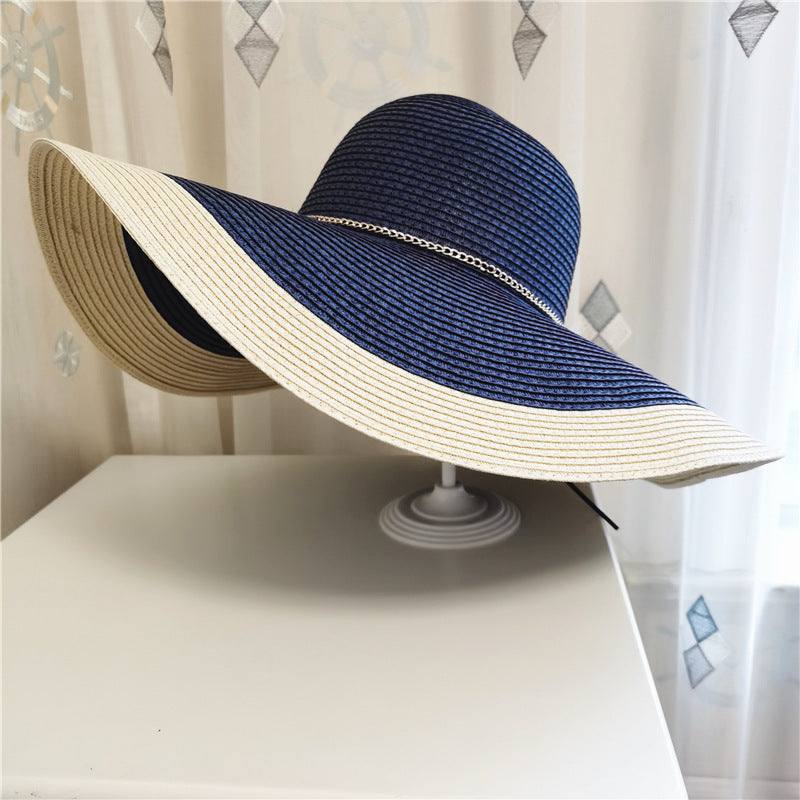 Large navy blue and beige straw beach hat with extended brim for summer sun protection.