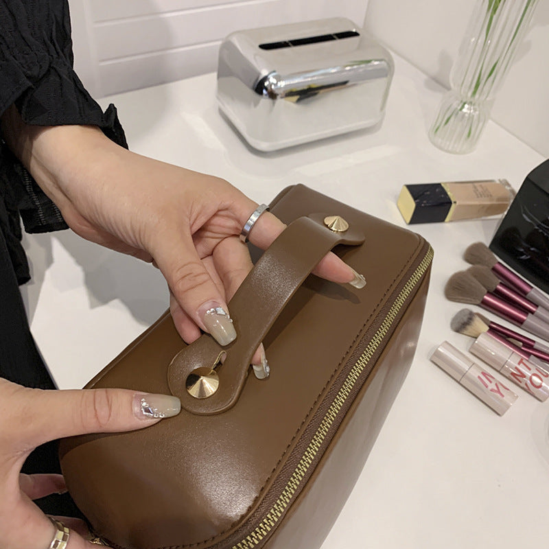 Cosmetic bag in brown PU leather with gold zipper, women's large capacity design.