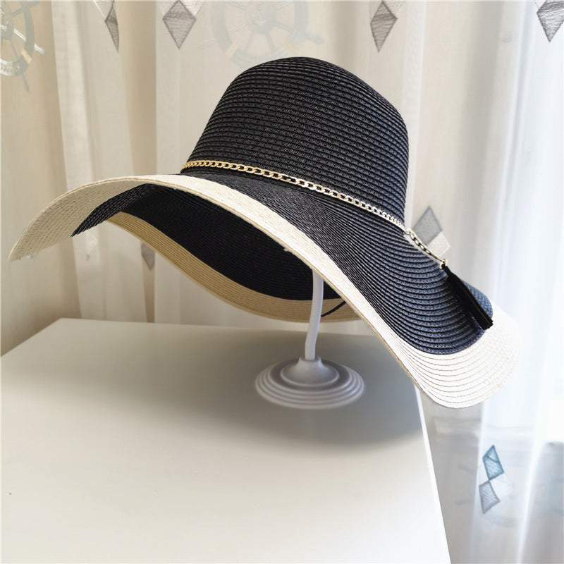 Summer sun protection big brim beach hat for women, made of straw with a flat top and extended brim in black and beige.