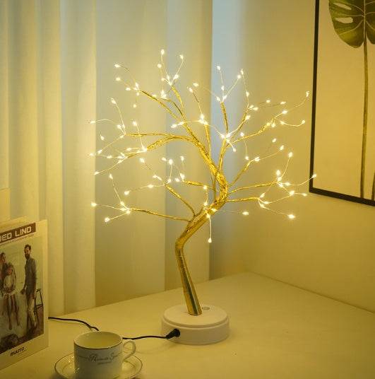 LED copper wire light shaped like a golden tree with warm white lights on a bedside table in a bedroom setting