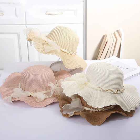 Wide-brimmed sun hats with pearl chain ribbons in white, beige, pink, and brown for beach travel.