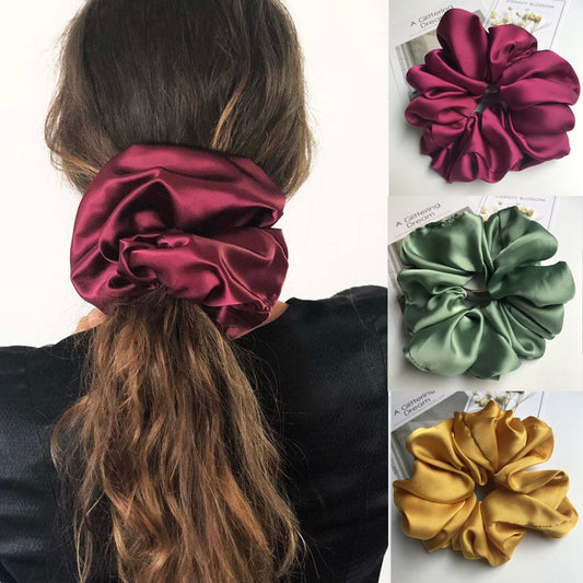 Oversized smooth satin scrunchie in burgundy, green, and yellow on model's hair and display.