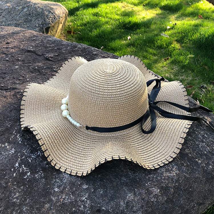 Women's straw hat with big brim on stone surface, featuring a dome top and bow, ideal for summer.