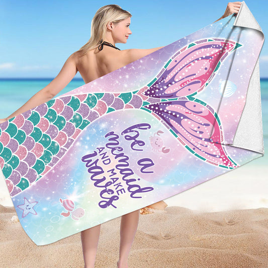 Mermaid-themed microfiber bath towel with colorful scales design on a beach.