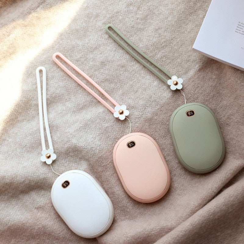 Mini power bank in pastel colors with floral strap on soft fabric background.