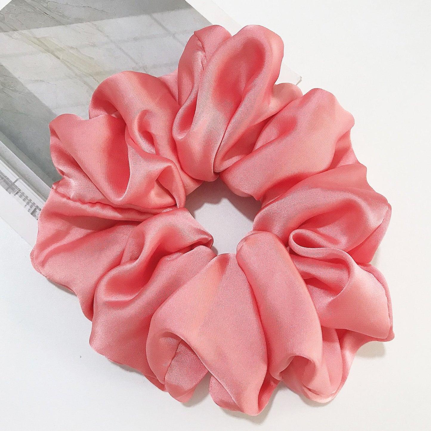 Oversized smooth satin large intestine circle hair tie in peach pink.