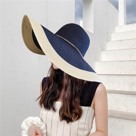 Summer sun protection big brim beach hat for women in navy blue and beige, straw material, flat top design.