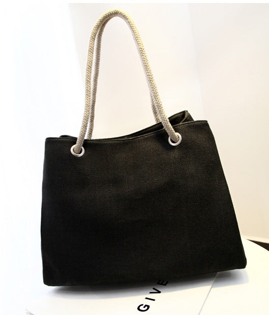 Large capacity black canvas shoulder bag with soft handles and woven design.