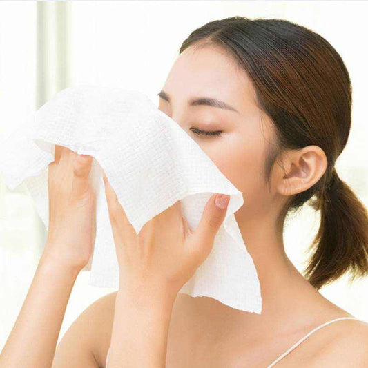 Woman using a compressed towel on her face, highlighting the portable and disposable features.