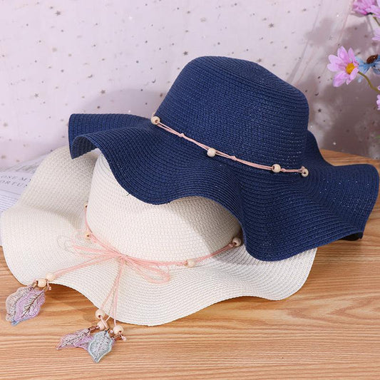 Ladies big brim wave straw hats in navy and beige with decorative bows.
