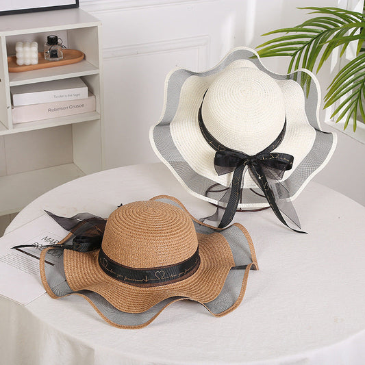 Elegant ladies mesh straw hats with big brims, decorated with streamers, in milk white and beige color options.