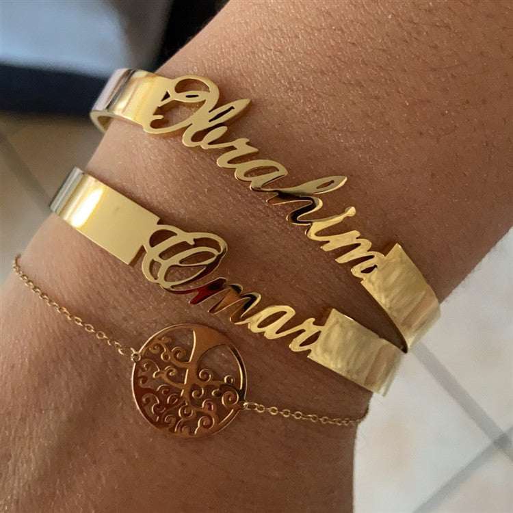 Customized name bracelet in gold on wrist, personalized stainless steel jewelry.